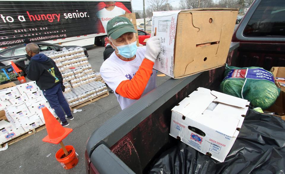 Volunteer John Anderson places a box of sweet potatoes in the back of a truck Thursday, Jan. 13, 2022, at the Mt. Zion Restoration Church on Crescent Lane in Gastonia.