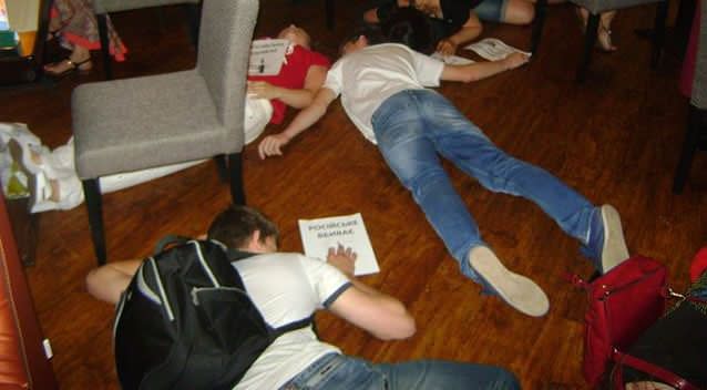 Protesters lying down on the floor with paper signs: Photo Facebook