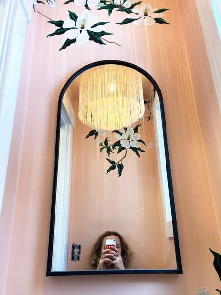 The powder room, featuring a hand-painted mural done by Bloom's mother and a custom light fixture, fabricated in Latvia and sourced from Etsy.