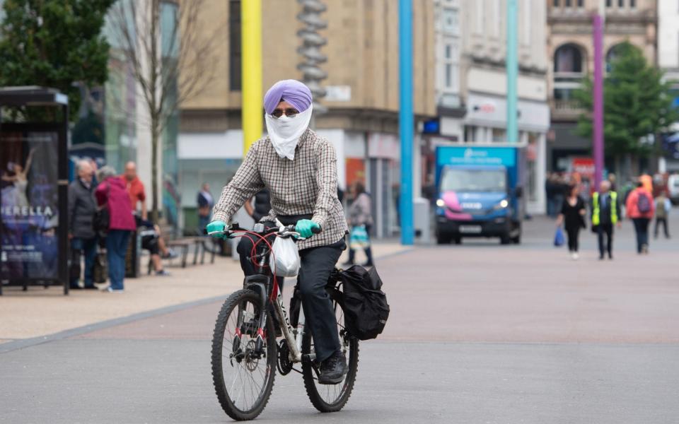 A man cycles through Leicester wearing a face mask - Joe Giddens/PA