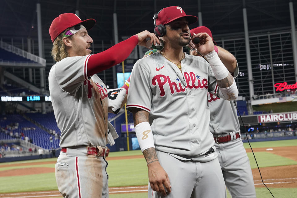 Teammates pour water on Philadelphia Phillies' Nick Castellanos as he is interviewed at the end of a baseball game against the Miami Marlins, Tuesday, Aug. 1, 2023, in Miami. Castellanos hit a two-run home run in the ninth inning. The Phillies defeated the Marlins 3-1. (AP Photo/Marta Lavandier)