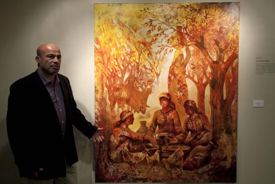 In this photo taken Saturday, May 10, 2014, Palestinian artist Maher Naji poses next to his acrylic on canvas painting named The Remaining Memory, during an art exhibition "Traces, a testimony to memory," displaying over forty Palestinian artists work from Gaza, in the West Bank city of Ramallah. The Gaza Strip is tough turf for artists. An Israeli-Egyptian border blockade of the Hamas-ruled territory keeps them away from an international audience and potential buyers, while the local art market is close to nil. A new exhibit now offers them a chance to showcase their work outside Gaza. (AP Photo/Nasser Nasser)