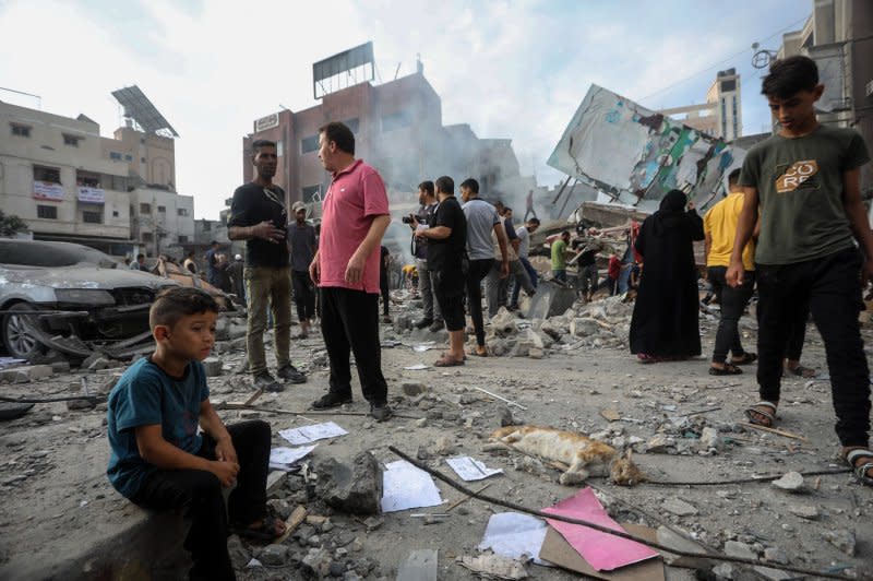 A Palestinian child sits while others inspect the destruction following Israeli airstrikes on Khan Younis, southern Gaza Strip on Tuesday. Photo by Ismael Mohamad/UPI
