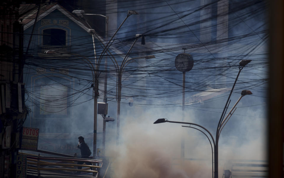 A supporter of former President Evo Morales runs among tear during clashes with security forces in La Paz, Bolivia, Friday, Nov. 15, 2019. Morales stepped down on Nov. 10 following nationwide protests over suspected vote-rigging in an election in which he claimed to have won a fourth term in office. An Organization of American States audit of the vote found widespread irregularities. (AP Photo/Natacha Pisarenko)