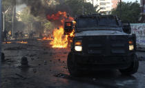Un vehículo blindado de la policía es incendiado al ser atacado por manifestantes en el primer aniversario del inicio de las protestas masivas contra el gobierno por la desigualdad en Chile, en Santiago, el domingo 18 de octubre de 2020. (AP Foto/Esteban Félix).