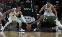 Milwaukee Bucks' Jrue Holiday, front right, dives for the ball as San Antonio Spurs' Dejounte Murray (5) and Devontae Cacok (17) defend during the first half of an NBA basketball in San Antonio, Texas, Saturday, Oct. 23, 2021. (AP Photo/Chuck Burton)