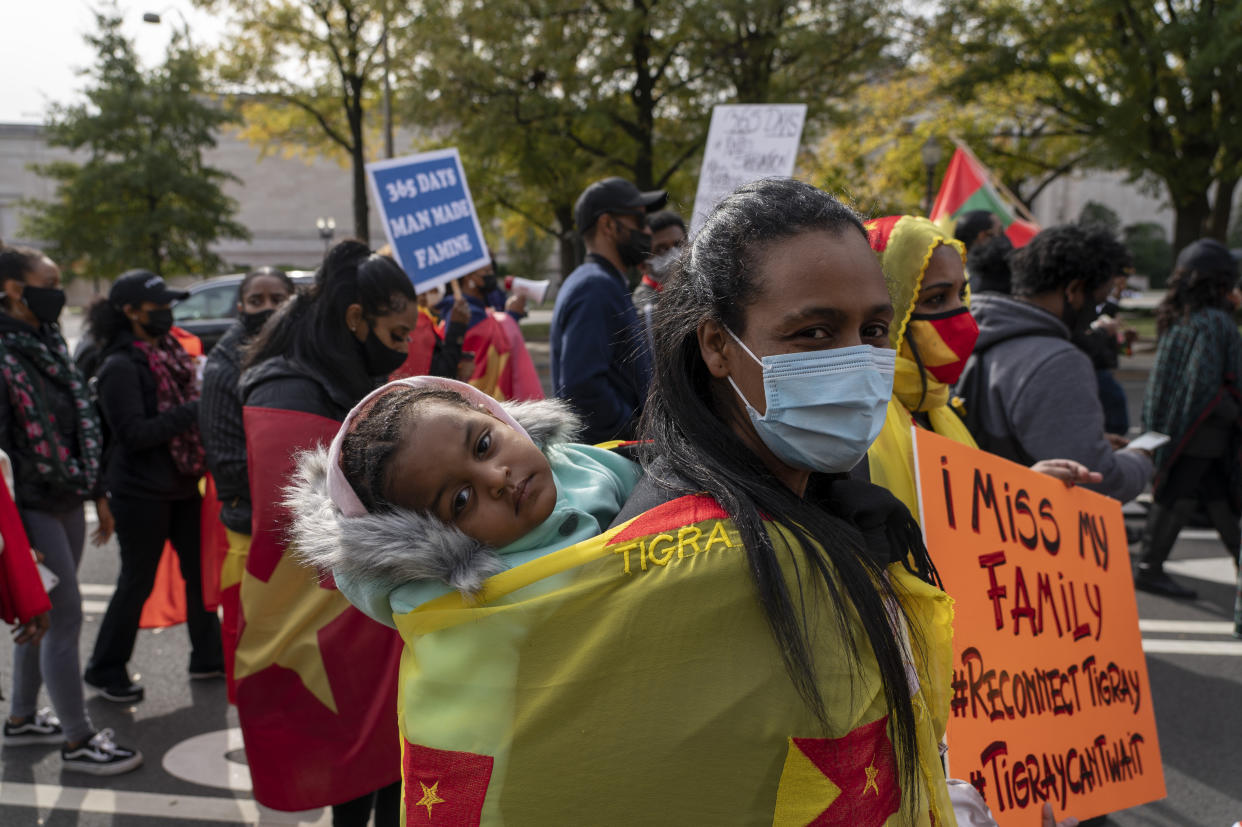 A woman carries a baby marching with exile Tigray community and their supporters to mark a year since Ethiopia Prime Minister Abiy Ahmed's administration started fighting against the Tigray, the northernmost region in Ethiopia, at the U.S. Capitol, Thursday, Nov. 4, 2021, in Washington. (AP Photo/Gemunu Amarasinghe)