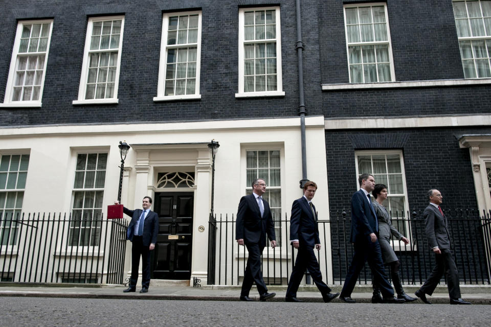 The treasury team of Britain's Chancellor of the Exchequer George Osborne, left, walk away as he poses for the media with his traditional red dispatch box outside his official residence at No 11 Downing Street in London, as he departs to deliver his annual budget speech to the House of Commons, Wednesday, March 21, 2012. Britain's finance minister was expected to announce tax breaks for both the top and the bottom of the nation's income scale Wednesday in his annual budget, but his room for maneuver was limited by the government's drive to slash borrowing and protect its AAA credit rating. (AP Photo/Matt Dunham)