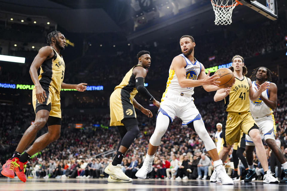 Golden State Warriors guard Stephen Curry (30) is guarded by Toronto Raptors' Immanuel Quickley (5), RJ Barrett and Kelly Olynyk (41) during the first half of an NBA basketball game Friday, March 1, 2024, in Toronto. (Arlyn McAdorey/The Canadian Press via AP)