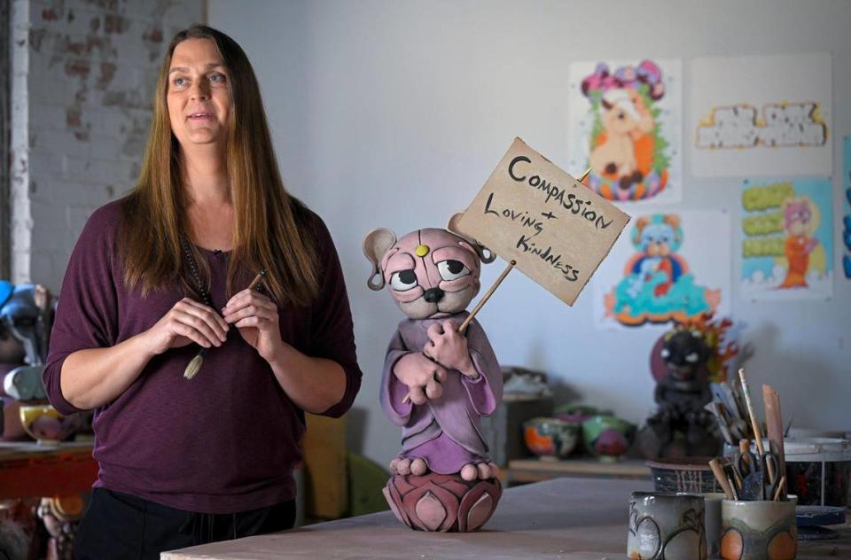 Heidi Schultz is an artist, teacher and a transgender woman, who lives in Kansas City and works in Kansas. She is seen in her studio with one of the clay Buddha buddies she made.