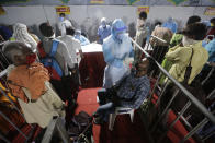 A health worker takes a nasal swab sample of a passenger to test for COVID-19 at a facility erected at a railway station to screen people coming from outside the city, in Ahmedabad, India, Friday, Sept. 18, 2020. India's coronavirus cases jumped by another 96,424 in the past 24 hours, showing little sign of leveling. India is expected to have the highest number of confirmed cases within weeks, surpassing the United States, where more than 6.67 million people have been infected. (AP Photo/Ajit Solanki)