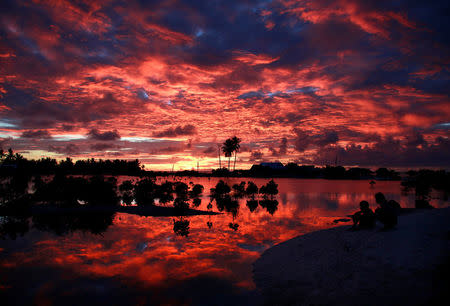 Villagers watch the sunset over a small lagoon near the village of Tangintebu on South Tarawa in the central Pacific island nation of Kiribati May 25, 2013. REUTERS/David Gray