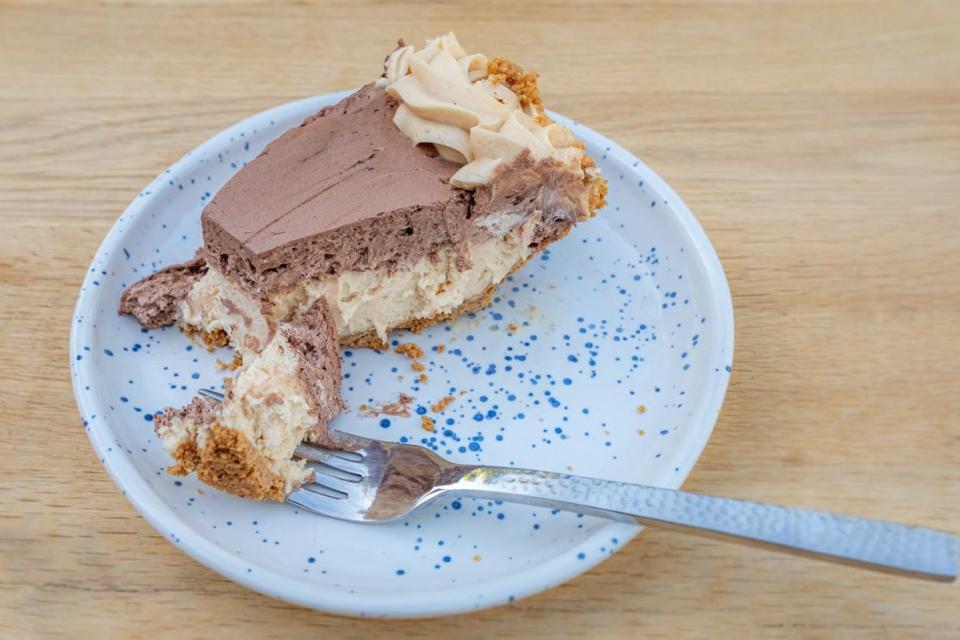 Slice of peanut butter and chocolate pie on speckled plate with fork dug into it 