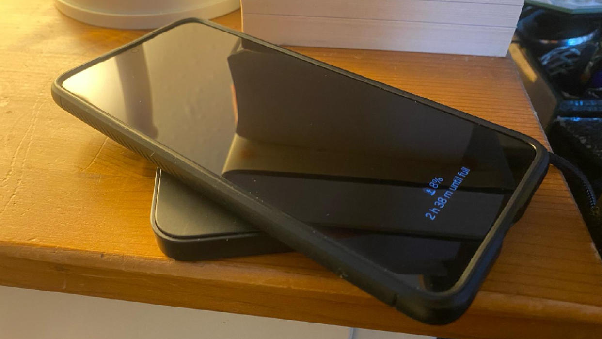  A Samsung S21+ on a wireless charger next to a bedside table. 