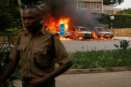 FILE PHOTO: A policeman runs past burning cars at the scene where explosions and gunshots were heard at the Dusit hotel compound, in Nairobi, Kenya January 15, 2019. REUTERS/Baz Ratner/File Photo