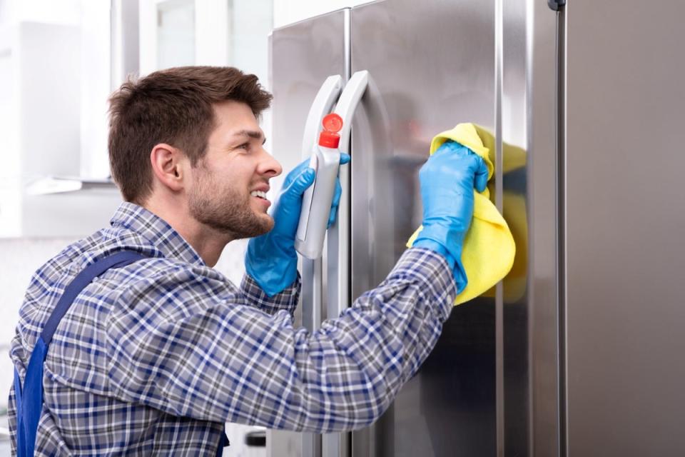 Young male touching up fridge.