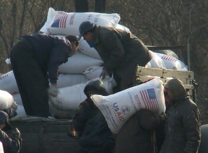 FILE PHOTO - Workers unload food aid from a truck in the Sinuiju region of North Korea in this picture taken on December 11, 2008 from a tourist boat on the Yalu River, which divides North Korea and China.  REUTERS/Stringer/File Photo