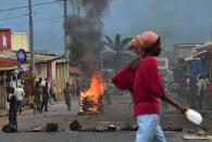 A woman walks past a burning barricade during a demonstration against the Burundian President in the Kinanira neighborhood of Bujumbura on May 21, 2015