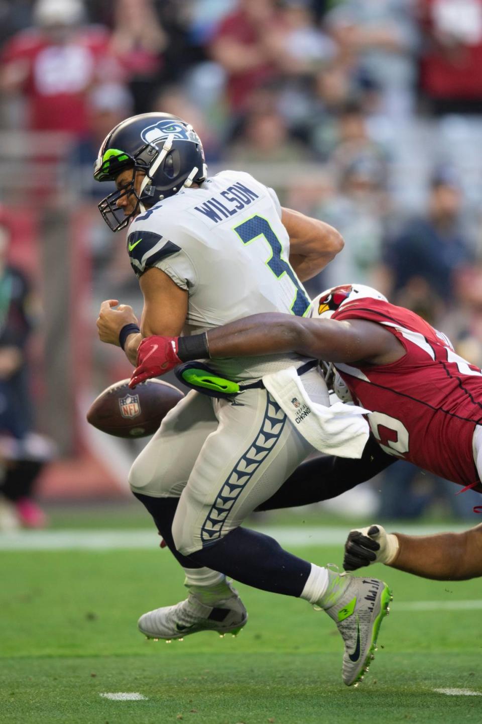 Seattle Seahawks quarterback Russell Wilson (3) has the ball stripped from him resulting in a first quarter touchdown by the Arizona Cardinals during an NFL Professional Football Game Sunday, Jan. 9, 2022, in Phoenix. (AP Photo/John McCoy)