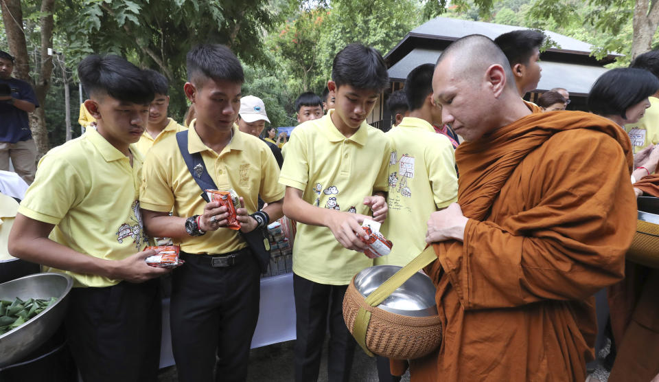 Members of the Wild Boars soccer team who were rescued from a flooded cave, offer foods to a Buddhist monk near the Tham Luang cave in Mae Sai, Chiang Rai province, Thailand Monday, June 24, 2019. The 12 boys and their coach attended a Buddhist merit-making ceremony at the Tham Luang to commemorate the one-year anniversary of their ordeal that saw them trapped in a flooded cave for more than two weeks. (AP Photo/Sakchai Lalit)