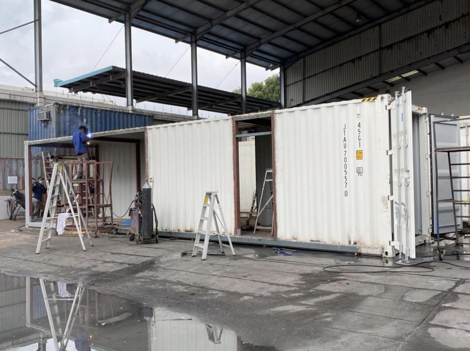 Shipping container being cut to fit windows.