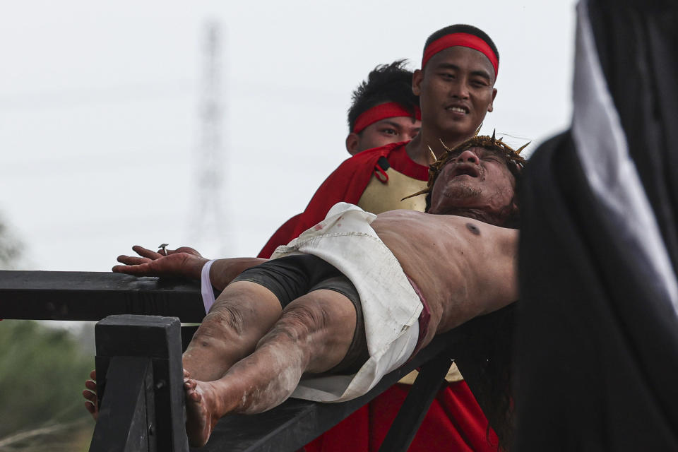 Ruben Enaje grimaces from being nailed to the cross during the reenactment of Jesus Christ's sufferings as part of Good Friday rituals in the San Pedro Cutud, north of Manila, Philippines, Friday, March 29, 2024. The Filipino villager was nailed to a wooden cross for the 35th time to reenact Jesus Christ’s suffering in a brutal Good Friday tradition he said he would devote to pray for peace in Ukraine, Gaza and the disputed South China Sea. (AP Photo/Gerard V. Carreon)