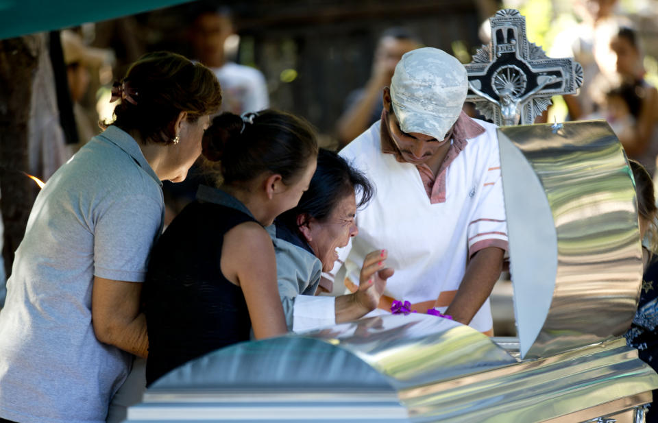 CORRECTS TO REMOVE THE WORD CROSSFIRE TO CLARIFY ALLEGED CIRCUMSTANCES- Juana Perez, third from left, cries beside the coffin of her son Rodrigo Benitez, 25, killed in the recent fighting in Antunez, Mexico, Tuesday, Jan. 14, 2014. The government moved in to quell violence between vigilantes and a drug cartel, and witnesses say several unarmed civilians were killed in an early Tuesday confrontation. According to family members at the funeral, Benitez died after soldiers opened fire on self-defense vigilantes and their supporters, after the crowd surrounded a military convoy and refused to let their vehicles proceed, amid fears the military was going to try to disarm the self-defense forces. (AP Photo/Eduardo Verdugo)