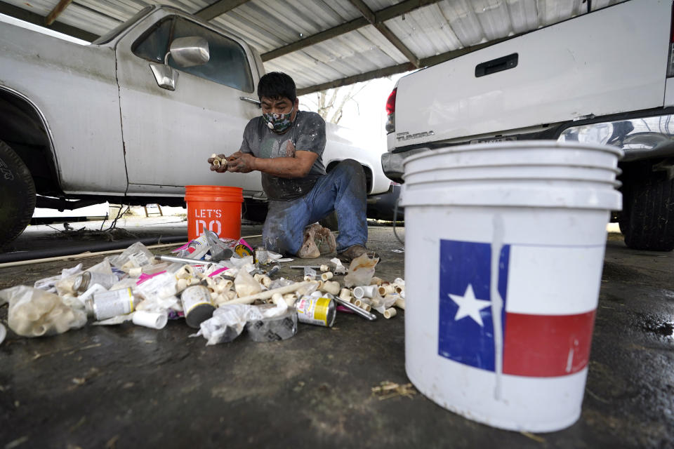 Martin Uribe, with West Street Recovery, sorts through plumbing repair parts while working to fix busted pipes which froze during the recent winter storm, at a home in Houston, Thursday, Feb. 25, 2021. West Street Recovery, a nonprofit created in the wake of Hurricane Harvey to help repair flood damaged homes, has been working since the winter storm hit to repair and replace damaged plumbing systems for residents who can't afford to do so. (AP Photo/David J. Phillip)