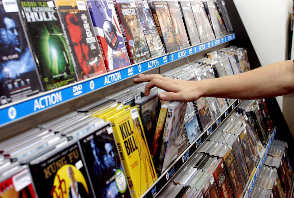 Person browsing through a selection of DVDs in a store, indicative of consumer choice in the entertainment market