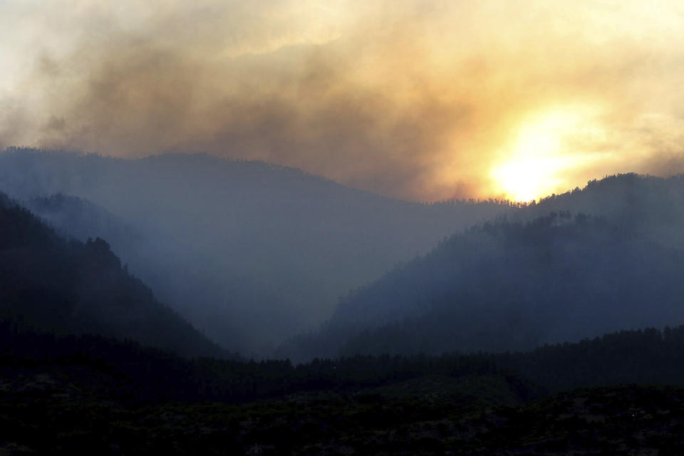 FILE - In this June 13, 2018 file photo, smoke rises from the 416 Fire near Durango, Colo., as the sun sets. The U.S. Attorney’s Office filed a lawsuit on Tuesday, July 2, 2019, alleging that the fire was sparked by the Durango & Silverton Narrow Gauge Railroad. The fire burned about 85 square miles making it the sixth largest in state history. (Jerry McBride/The Durango Herald via AP, File)