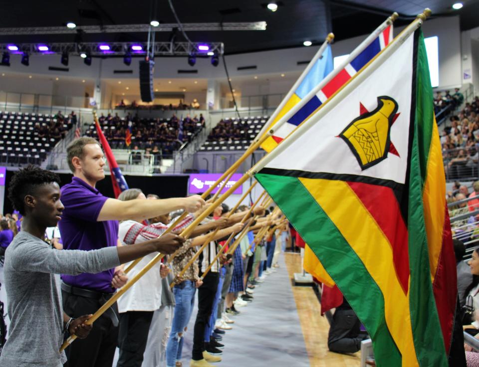 The flag of Zimbabwe, held by freshman nursing major Caleb Onzi, is displayed next to that of the United Kingdom at Monday's opening assembly.
