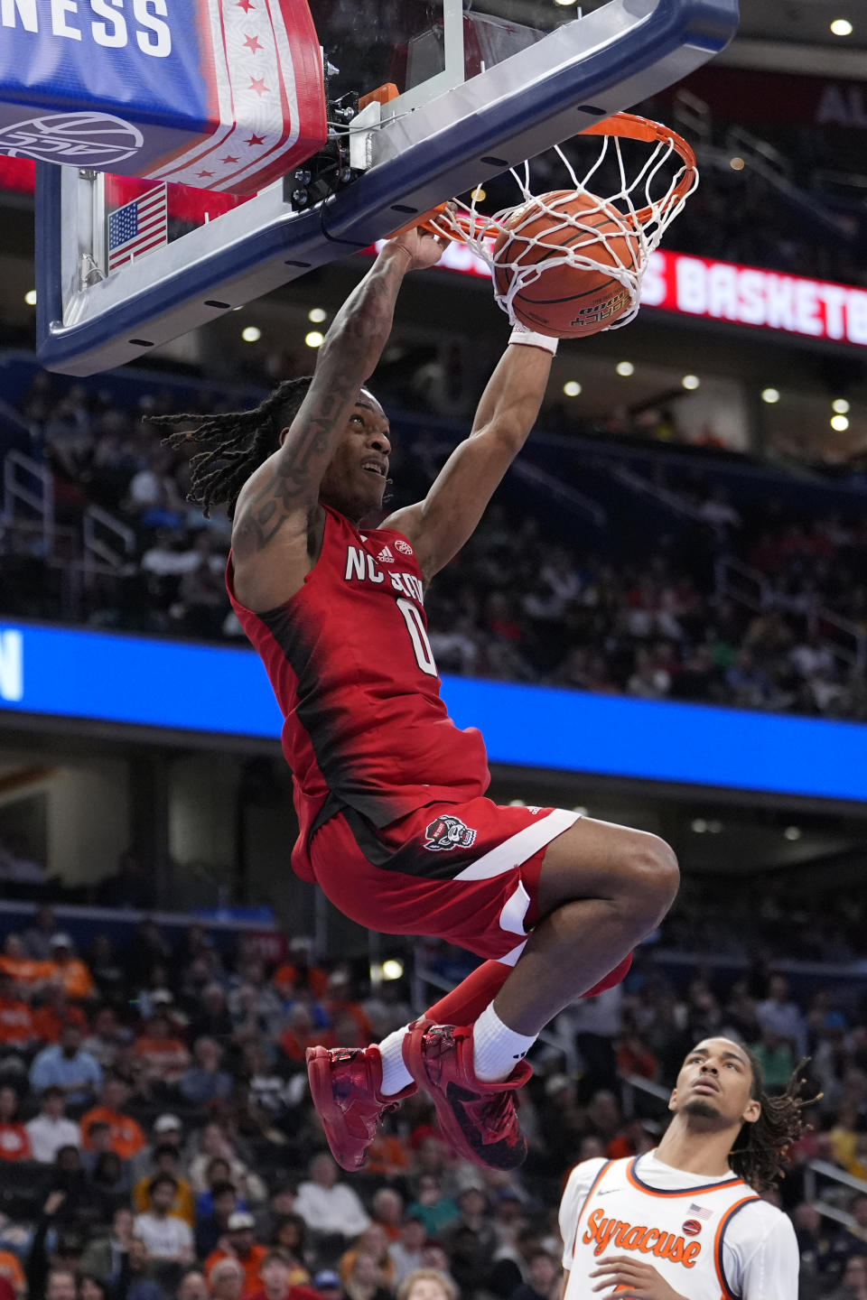 North Carolina State guard DJ Horne (0) dunks as Syracuse forward Chris Bell (4) looks on during the second half of the Atlantic Coast Conference NCAA college basketball tournament Wednesday, March 13, 2024, in Washington. (AP Photo/Alex Brandon)