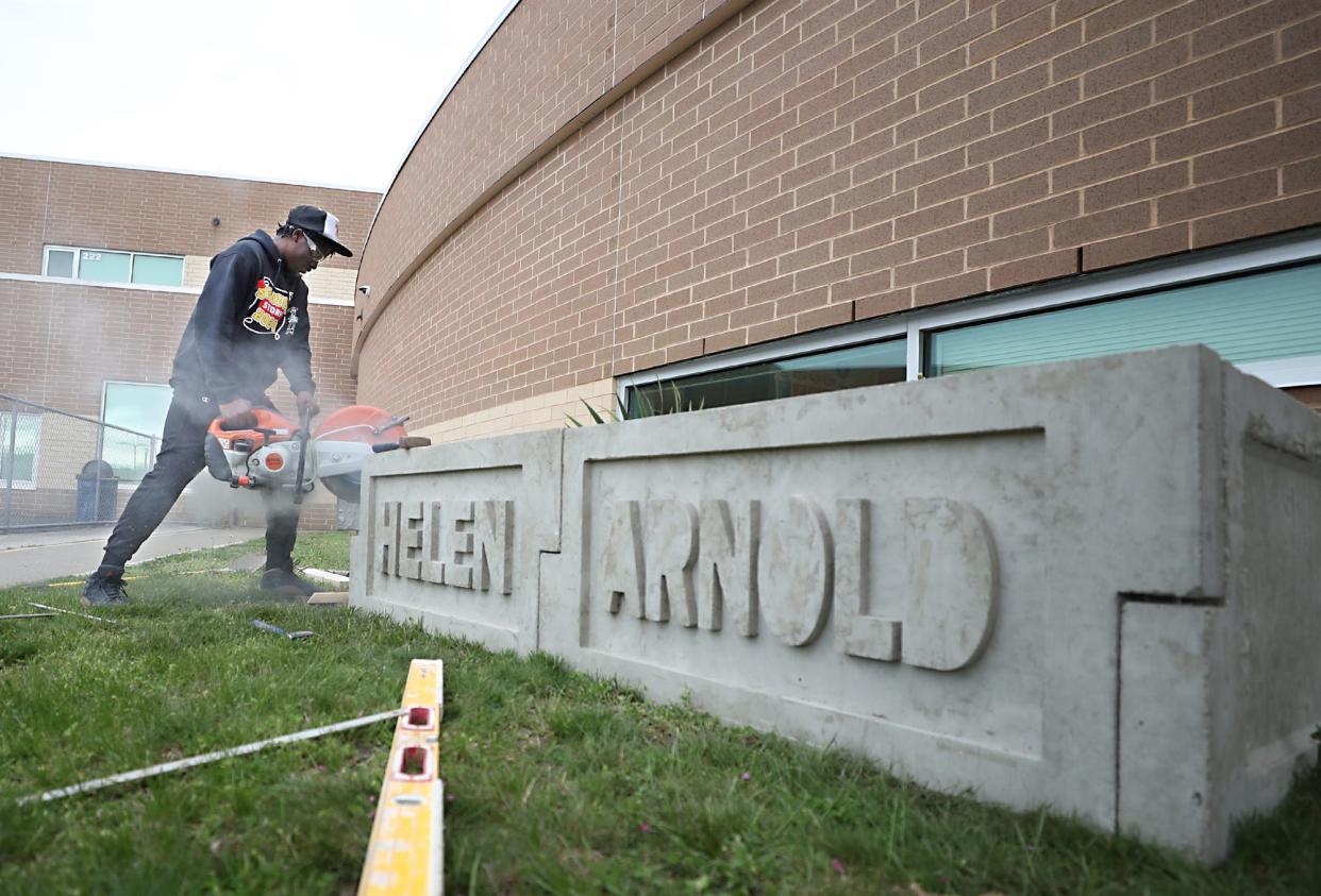 Ryen Finney-Kimble, 18, a Buchtel Community Learning Center masonry student, uses a concrete saw to trim the edge of a formed concrete side for a better fit of a new garden bed at Helen Arnold CLC on Wednesday.