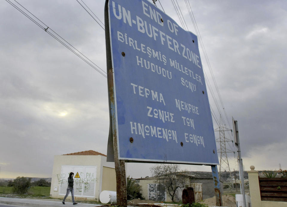 FILE - A woman walks by a UN sign at the UN buffer zone inside Pyla village, outskirt of coastal city of Larnaca, Cyprus, Thursday, Jan. 8, 2009. Three United Nations soldiers had to be treated for minor injuries after angry Turkish Cypriots punched and kicked a group of peacekeepers who obstructed crews working on a road that would encroach on a U.N.-controlled buffer zone in ethnically divided Cyprus. The U.N. said Friday, Aug. 18, 2023, the assault happened as peacekeepers stood in the way of work crews building a road to connect the village of Arsos in the breakaway Turkish Cypriot north with the mixed Greek Cypriot-Turkish Cypriot village of Pyla. (AP Photo/Petros Karadjias, File)