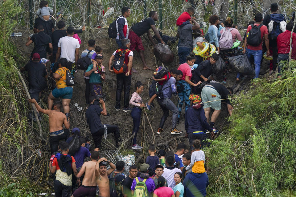 Migrants stand on the bank of the Rio Grande river as Texas National Guards block them from behind razor wire, seen from Matamoros, Mexico, Thursday, May 11, 2023. Pandemic-related U.S. asylum restrictions, known as Title 42, are to expire May 11. (AP Photo/Fernando Llano)