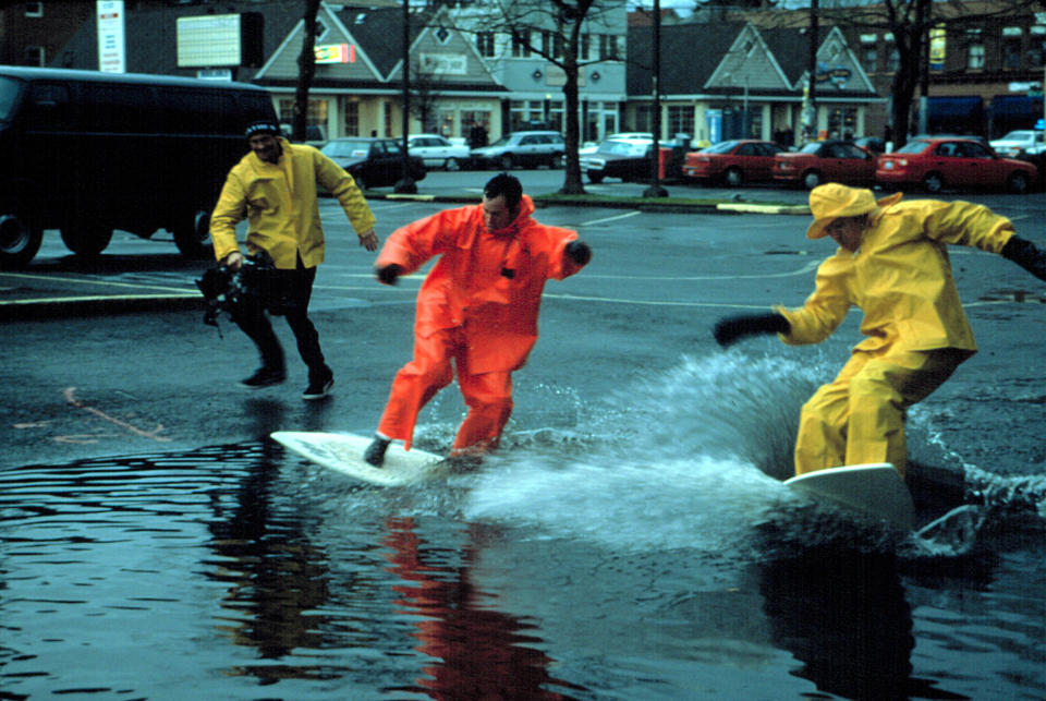 The jackass guys surfing on a flooded road