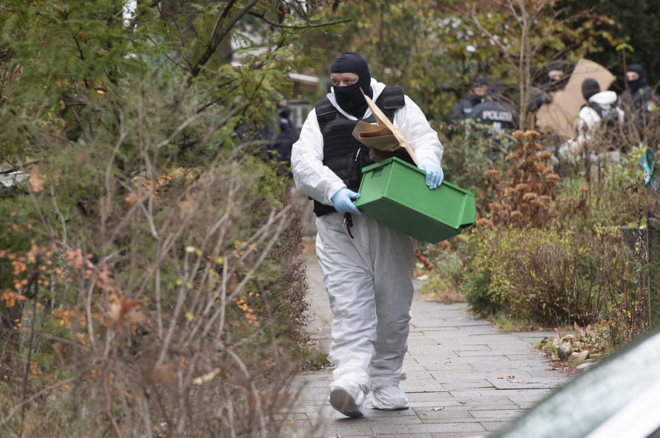 A police officer carries a plastic box during a raid against so-called 'Reich citizens' in Berlin, Germany, Wednesday, Dec. 7, 2022. Thousands of police carried out a series of raids across much of Germany on Wednesday against suspected far-right extremists who allegedly sought to overthrow the state by force. Federal prosecutors said some 3,000 officers conducted searches at 130 sites in 11 of Germany's 16 states against adherents of the so-called Reich Citizens movement. Some members of the grouping reject Germany's postwar constitution and have called for the overthrow of the government. (Paul Zinken/dpa via AP)