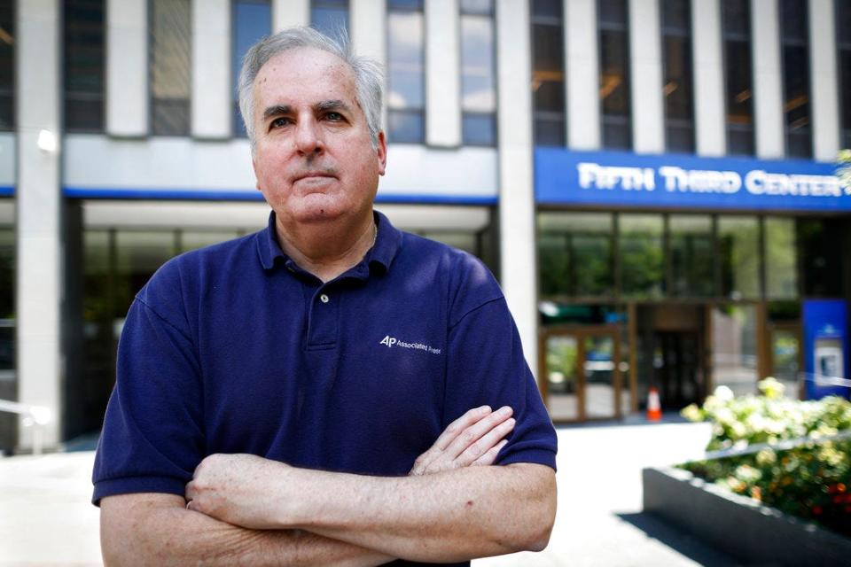 In this Friday, Sept. 14, 2018 photo, Associated Press senior correspondent Dan Sewell poses for a photograph outside the scene of a shooting that occurred the previous week at Fountain Square, in Cincinnati. "Over four decades with The Associated Press, I have many times thrown clothes into a bag, withdrawn a wad of cash, and stuffed my laptop with notebooks and pens before rushing by car or plane to a terrible event in someone else's hometown, state or country," said Sewell. "This time, it was in my town." (AP Photo/John Minchillo)