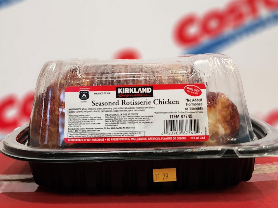 Container of Costco rotisserie chicken against a background with "Costco" on it