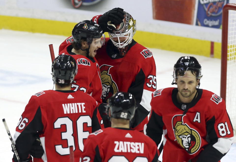 Ottawa Senators goaltender Marcus Hogberg (35) celebrates with teammates Thomas Chabot (72), Colin White (36), Ron Hainsey (81) and Nikita Zaitsev (22) following their third-period NHL hockey game win over the Calgary Flames in Ottawa, Ontario, Saturday, Jan. 18, 2020. (Fred Chartrand/The Canadian Press via AP)