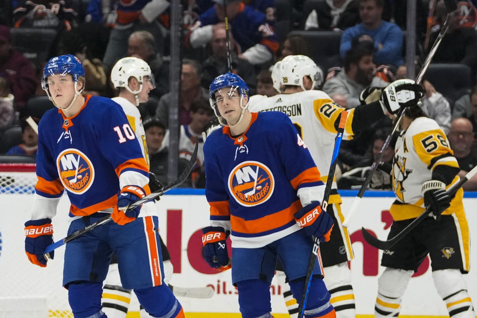 New York Islanders' Simon Holmstrom (10) and Samuel Bolduc (4) skate away as the Pittsburgh Penguins celebrate a goal by Evgeni Malkin during the second period of an NHL hockey game Wednesday, Dec. 27, 2023, in Elmont, N.Y. (AP Photo/Frank Franklin II)
