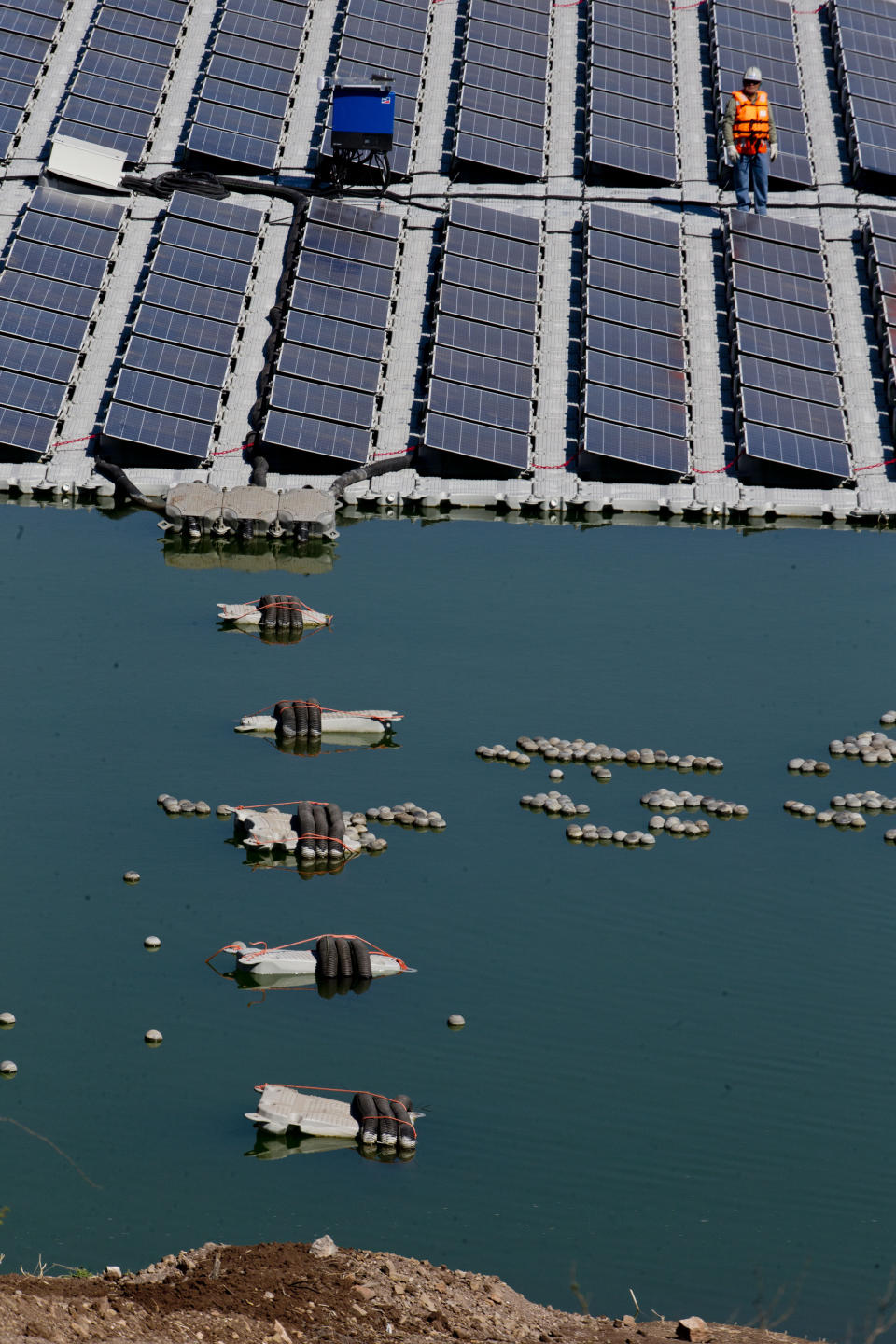 A worker stands on a floating island of solar panels at Los Bronces mine, about 65 kilometers (approximately 40 miles) from Santiago, Chile, Thursday, March 14, 2019. If the yearlong experiment works as planned, the solar panel island could be expanded and new ones could be installed at other mining ponds. Experts say there are approximately 800 such ponds in Chile. (AP Photo / Esteban Felix)