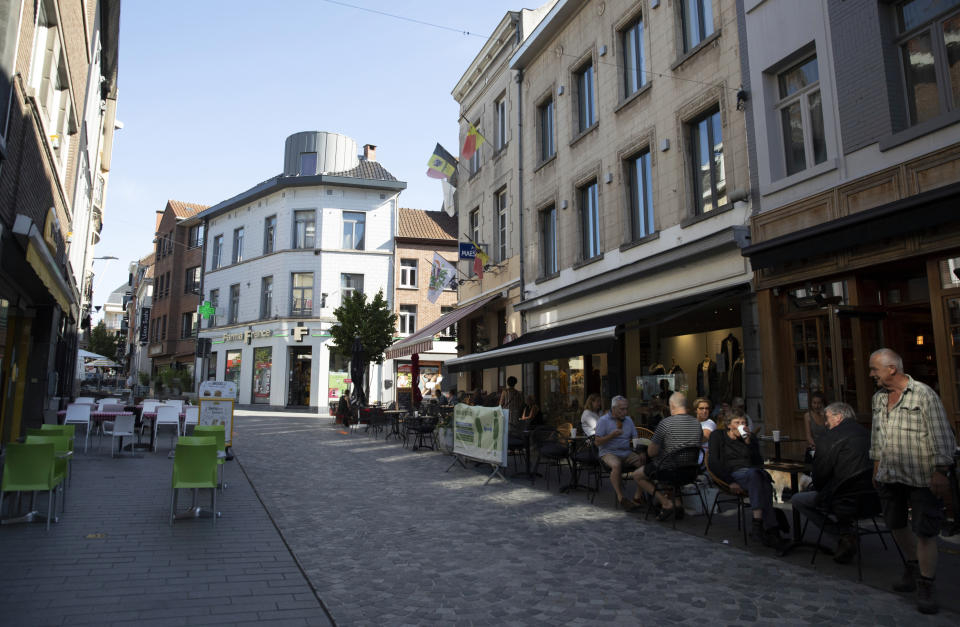 In this photo taken on Wednesday, June 24, 2020, people gather at an outdoor cafe on a shopping street in Halle, Belgium. In Halle, a small trading town of 40,000, as across much of Europe, the tide is turning and a new consciousness is taking shape in the wake of the Black Lives Matter movement in the United States. (AP Photo/Virginia Mayo)