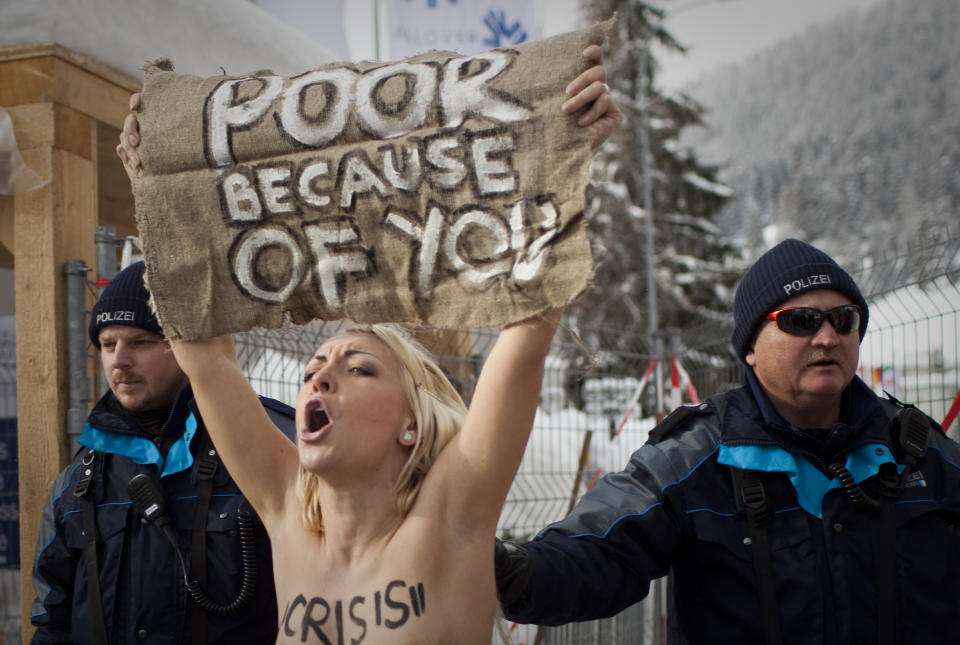 FILE - A topless Ukrainian protester is arrested by Swiss police after climbing up a fence at the entrance to the center where the World Economic Forum is held in Davos, Switzerland Saturday, Jan. 28, 2012. The activists are from the group Femen, which had become popular in Ukraine for staging small, half-naked protests against a range of issues including oppression of political opposition. (AP Photo/Anja Niedringhaus, File)