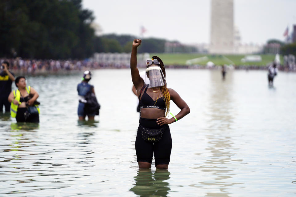 People pose for a photo in the Reflecting Pool in the shadow of the Washington Monument as they attend the March on Washington, Friday, Aug. 28, 2020, at the Lincoln Memorial in Washington, on the 57th anniversary of the Rev. Martin Luther King Jr.'s "I Have A Dream" speech. (AP Photo/Julio Cortez)