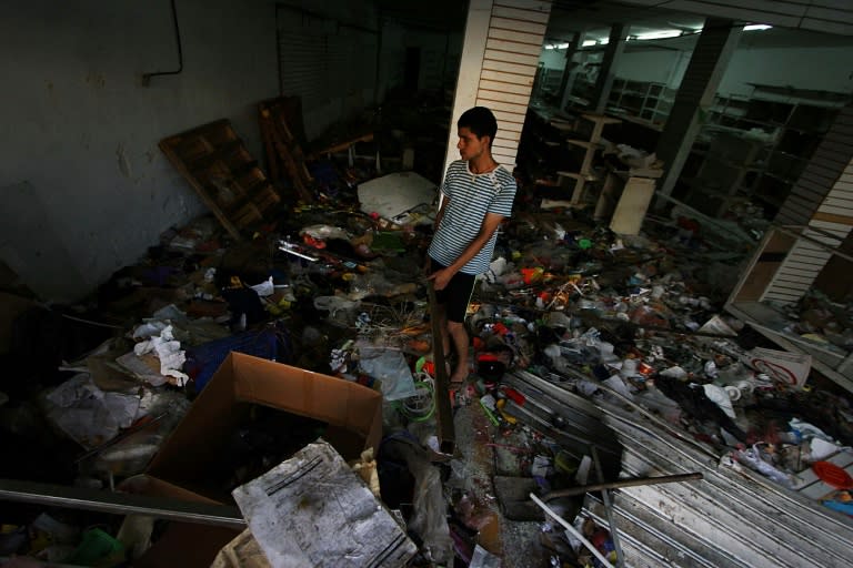 An employee of a looted supermarket inspects the damage in La Fria, Venezuela's Tachira state, in 2016