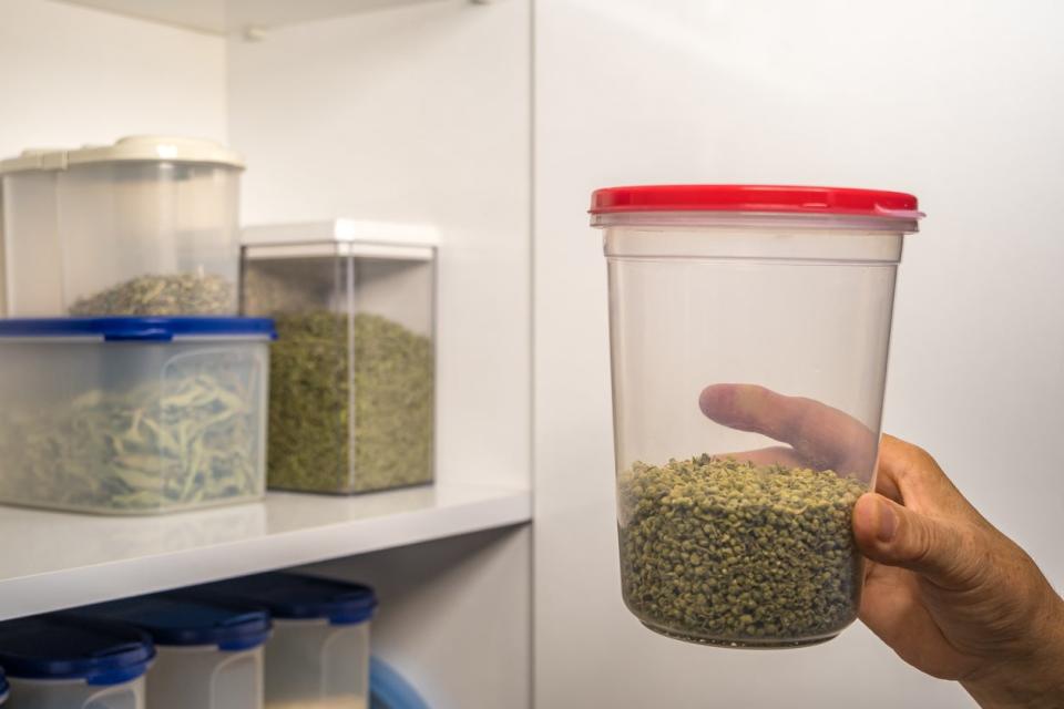Person taking thyme from shelf in number 5 plastic storage container
