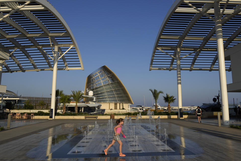 A girl runs by fountains at the new construction of "Ayia Napa Marina", in Ayia Napa resort in the eastern Mediterranean island of Cyprus, on Tuesday, June 6, 2023. When the U.S. and U.K. in April included a handful of Cypriot nationals and Cyprus-registered companies as part of another global crackdown on 'enablers' helping Russian oligarchs skirt sanctions, the perception that the island nation somehow remains Moscow's financial lackey again loomed large. (AP Photo/Petros Karadjias)