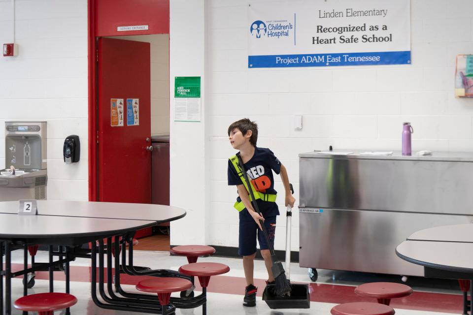 A member of the safety patrol helps clean up the cafeteria on their first day of school at Linden Elementary School in Oak Ridge, Tenn. on Monday, July 24, 2023.