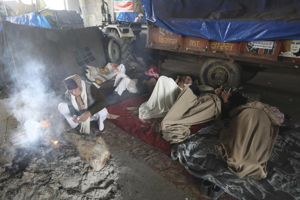 An Indian Farmer tries to light a fire as others rest under a flyover as they continue to block highway leading to Delhi in protest against new farm laws, at Delhi-Uttar Pradesh border, India, Friday, Jan. 22, 2021. Talks between protesting farmers’ leaders and the government ended abruptly in a stalemate on Friday with the agriculture minister saying he has nothing more to offer than suspending contentious agricultural laws for 18 months. The farmers’ organizations in a statement on Thursday said they can’t accept anything except the repeal of the three new laws. (AP Photo/Manish Swarup)